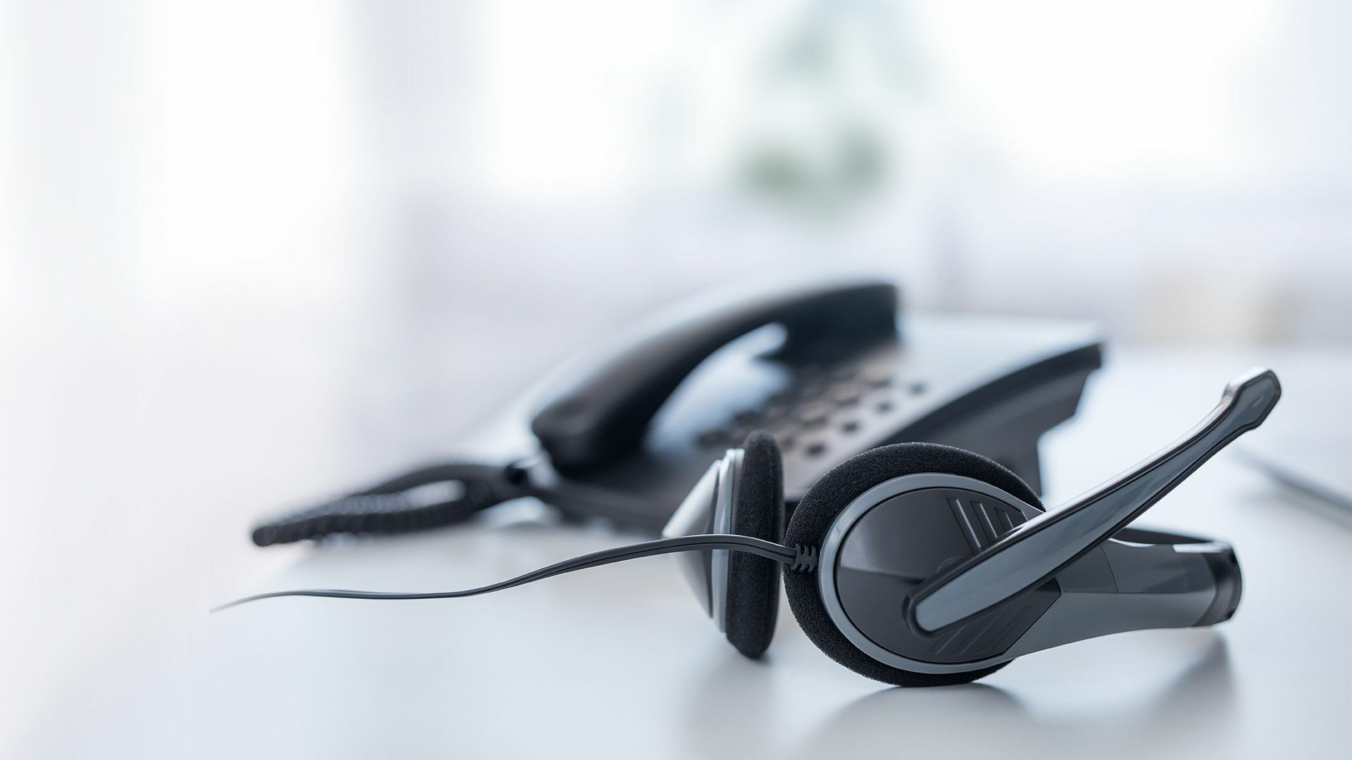Ein Telefon und ein Headset auf einem Schreibtisch in einem Büro